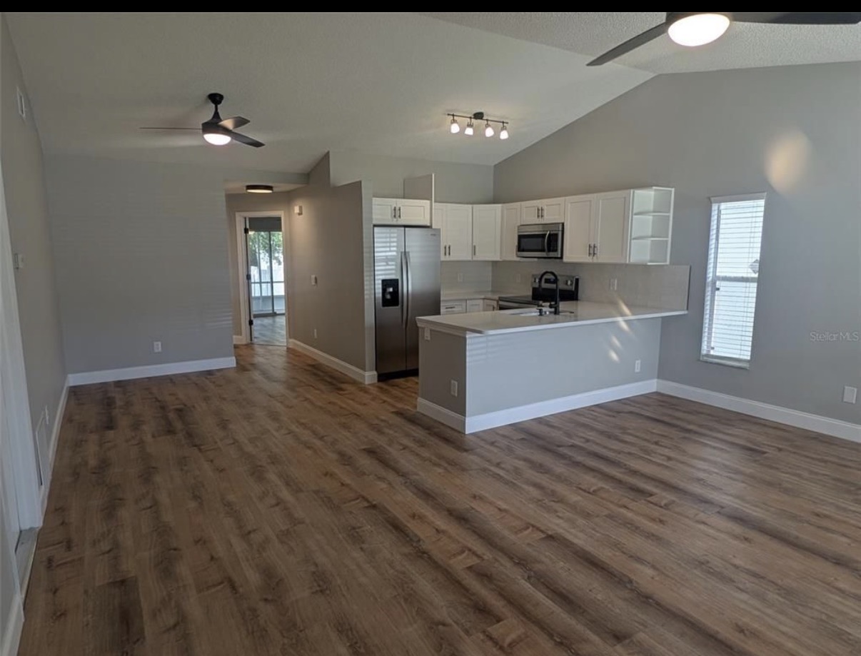 White kitchen opening onto a living room with wood-look flooring