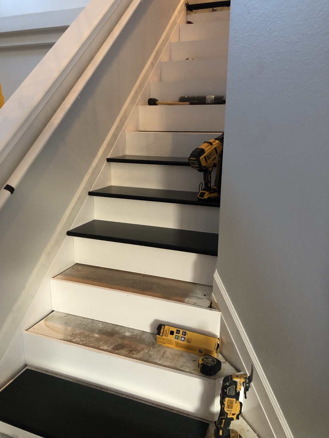 Black treads and white risers being installed, with tools visible