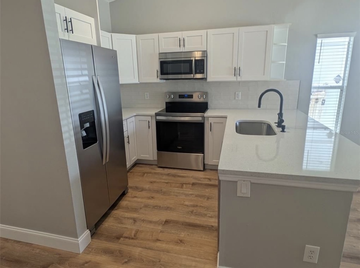 Remodeled kitchen with white cabinets, a light countertop and wood-look flooring